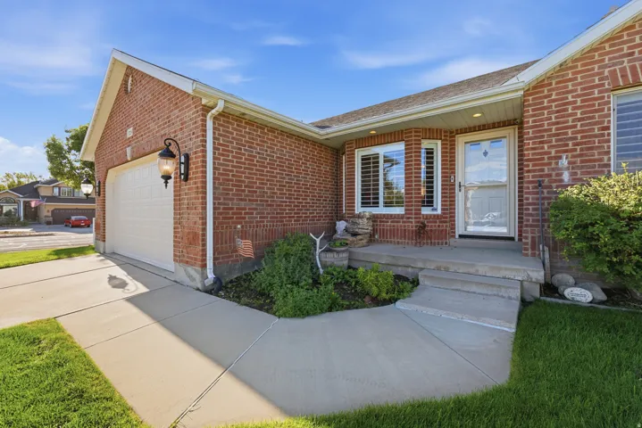Brick exterior with an attached garage, concrete driveway, and front walkway