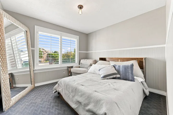 Window with plantation shutters, beadboard wainscoting, and patterned carpet