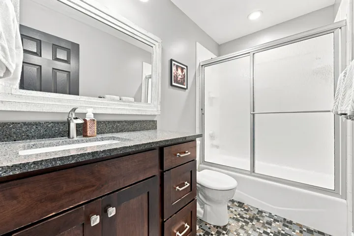 Dark wood-finish vanity with ample storage, a speckled countertop, and an undermount sink