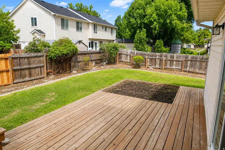 Wood deck with an integrated planter, fenced yard, and green lawn