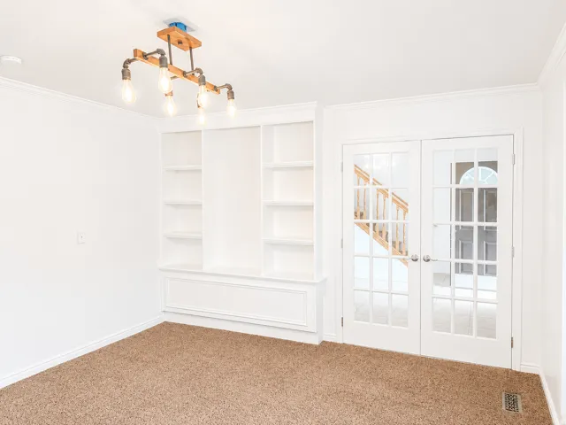 White built-in shelving, two French doors with clear glass panes, and a modern industrial-style light fixture
