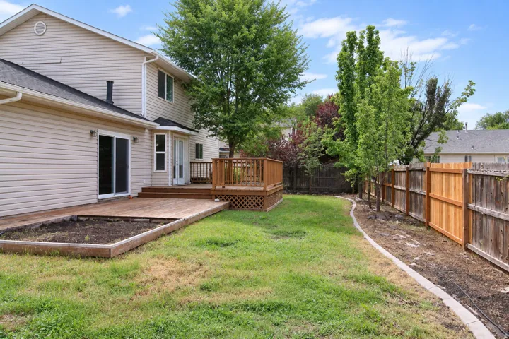 Expansive backyard featuring a wood deck with railings, a built-in planter box, and a combination of wood and privacy fencing