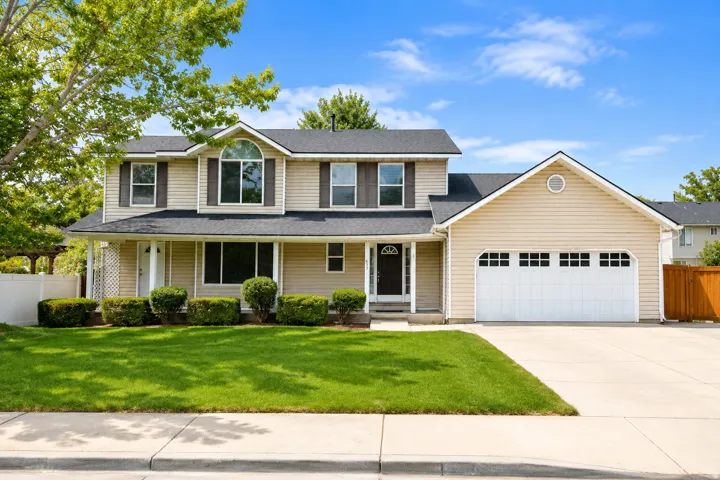 Two-story residence featuring light-colored siding, a black shingle roof, and a two-car garage