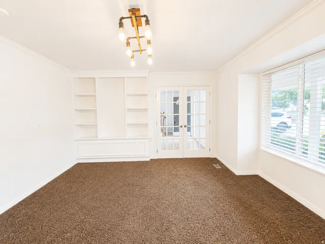 Bright, light-filled room showcasing neutral carpet flooring, recessed shelving with clean lines, and dual windows with plantation shutters