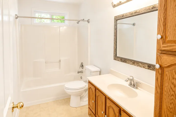 Spa-inspired bathroom featuring a wood-finish vanity with dual-sink configuration, cream-colored countertop, and brushed nickel fixtures