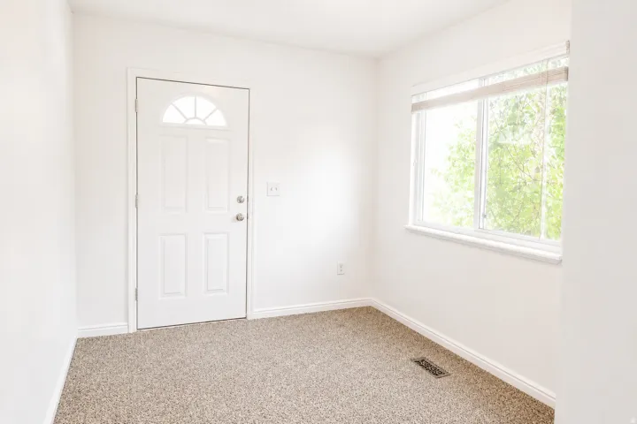 Entryway featuring a panel door with an arched window, a large picture window, and neutral-toned carpeting