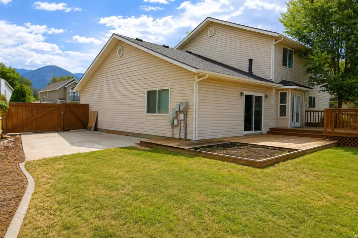 Expansive backyard featuring a manicured lawn, a large concrete pad, and a wooden deck