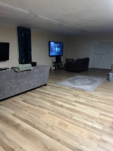 Wood-finish flooring throughout, complemented by a tiled accent wall and white bi-fold doors