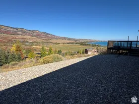 Expansive outdoor space featuring a wood deck, gravel area, and distant lake