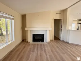 Spacious room with wood-finish flooring, a fireplace with a mantel and tiled surround, and large windows
