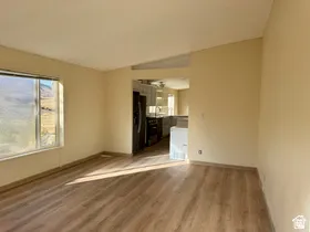 Wood-finish flooring throughout, neutral wall paint, and a pass-through opening to the kitchen