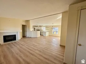 Wood-finish flooring throughout, featuring a fireplace with a light-toned surround and mantel