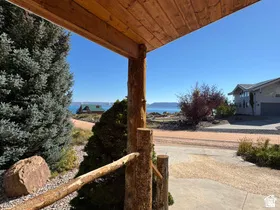 Wood-clad porch ceiling with natural wood posts, gravel landscaping, and mature evergreen trees
