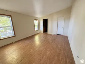 Vaulted ceiling, wood-finish flooring, two windows with wood trim, and two interior doors