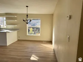 Open-concept living space with wood-finish flooring, a contemporary chandelier, and a breakfast bar with countertop seating