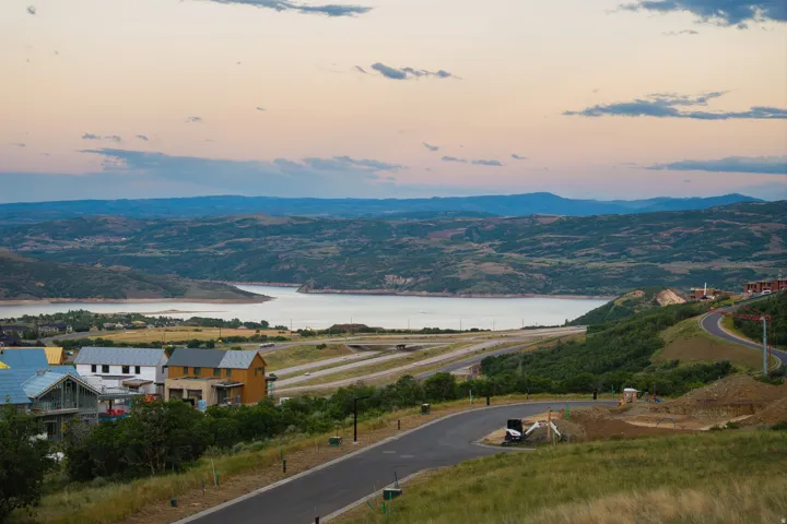 Mountainous landscape with a prominent lake, paved roadways, and residential structures