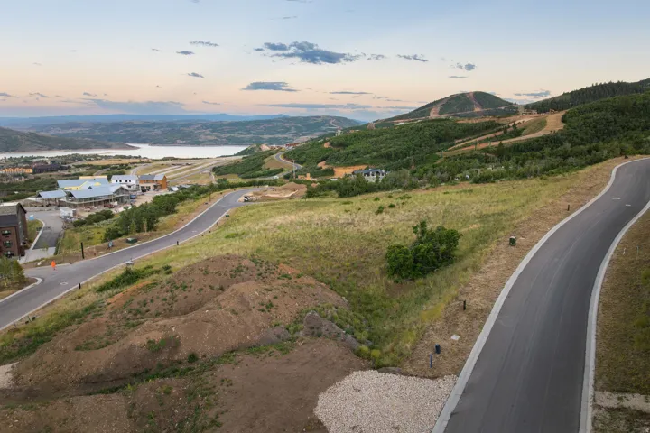 Paved roadways traversing a developing hillside community, featuring distant water body and mountainous terrain