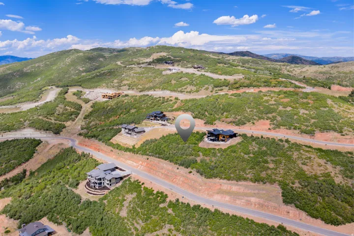 Mountainous terrain with expansive undeveloped land, winding roadways, and scattered residential properties