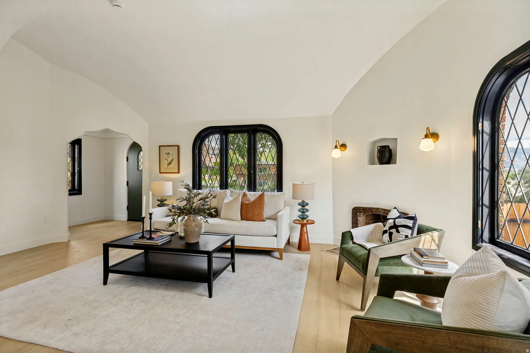 Arched doorways and windows with diamond-patterned grilles, a built-in wall niche, and wood-finish flooring