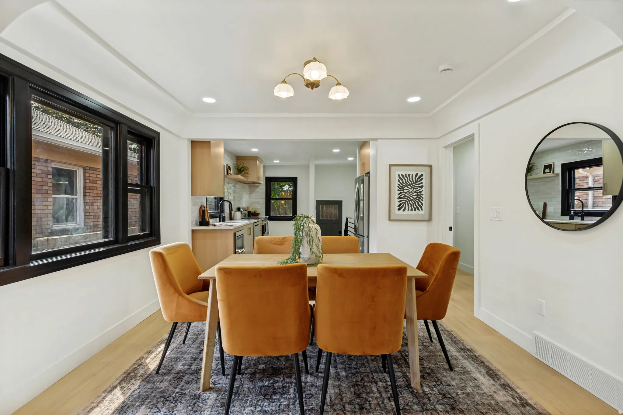 Recessed lighting, wood-finish flooring, black window trim, chandelier, and a built-in kitchen featuring light wood cabinetry