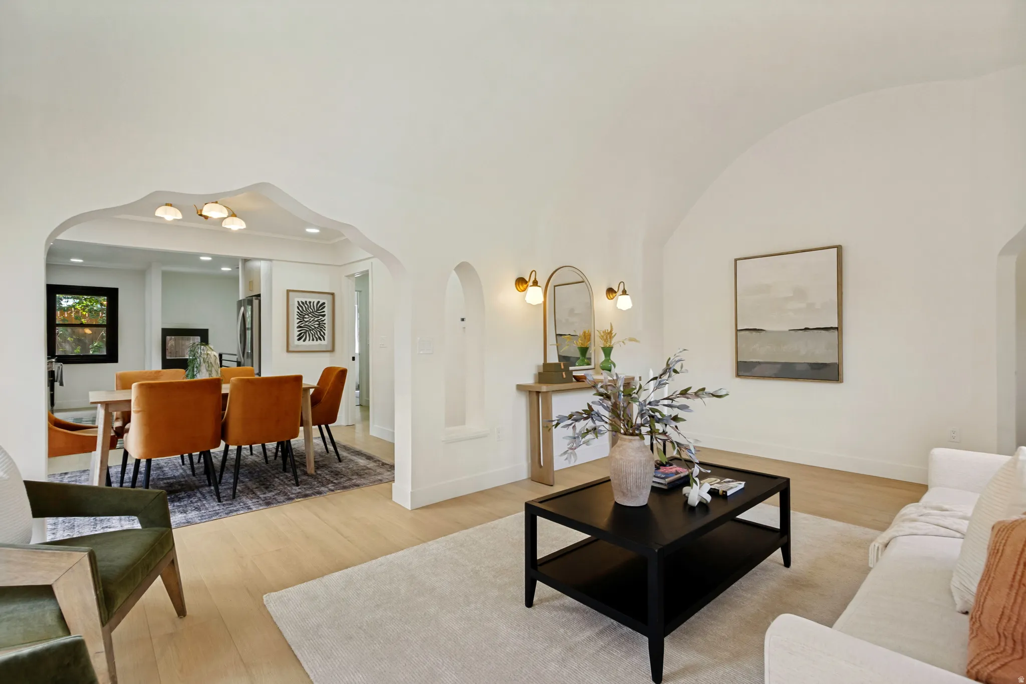 Vaulted ceiling, arched doorways, wood-finish flooring, recessed wall niche, and modern wall sconces