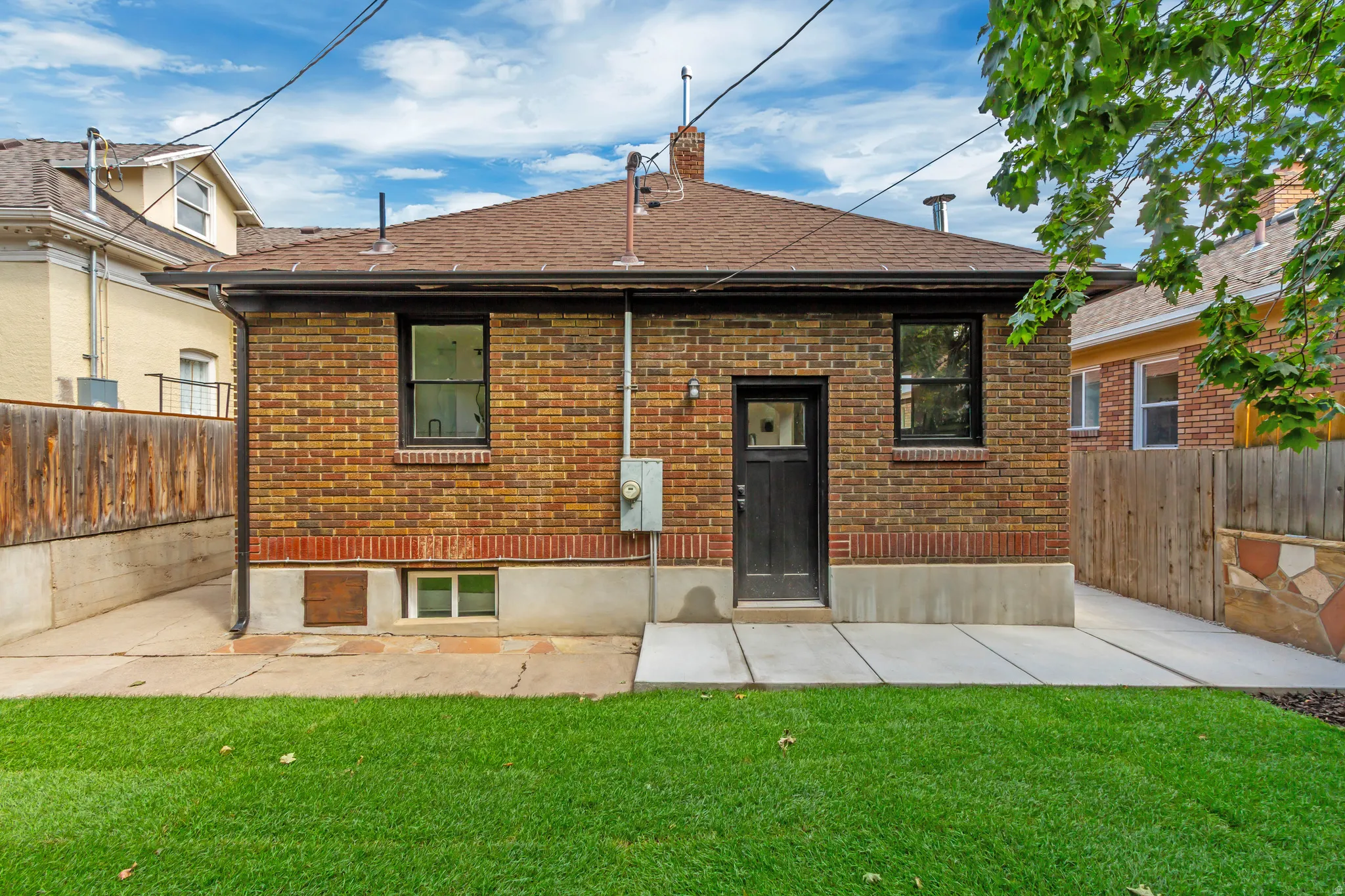 Brick exterior with a brown shingle roof, black-framed windows, and a black paneled door