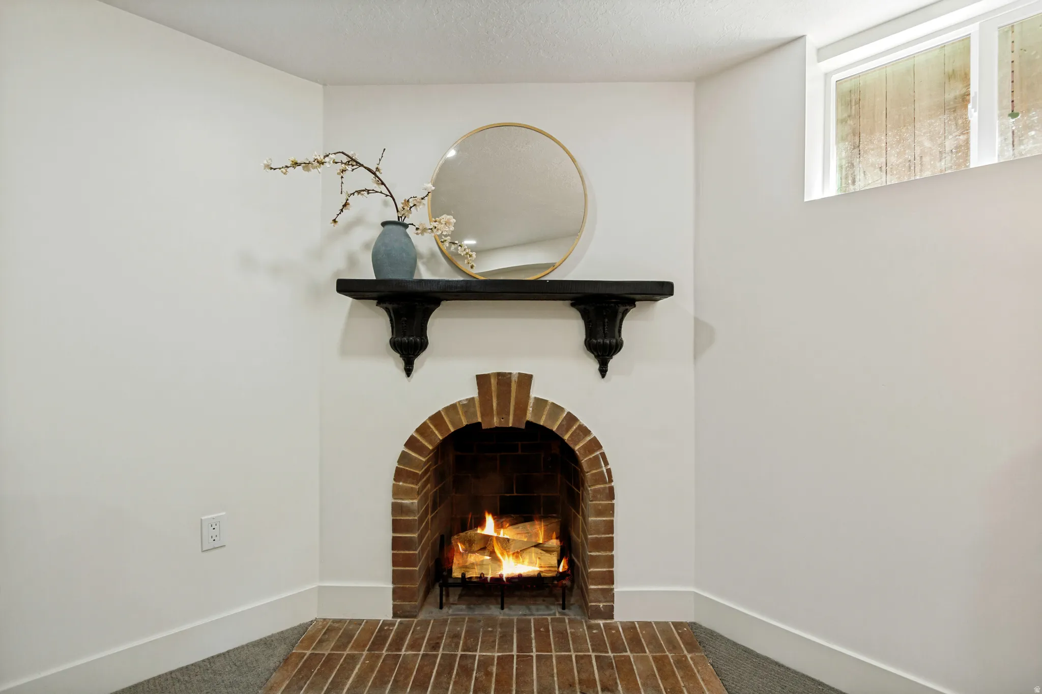 Brick-lined fireplace with an arched opening, detailed mantel, and a brick hearth