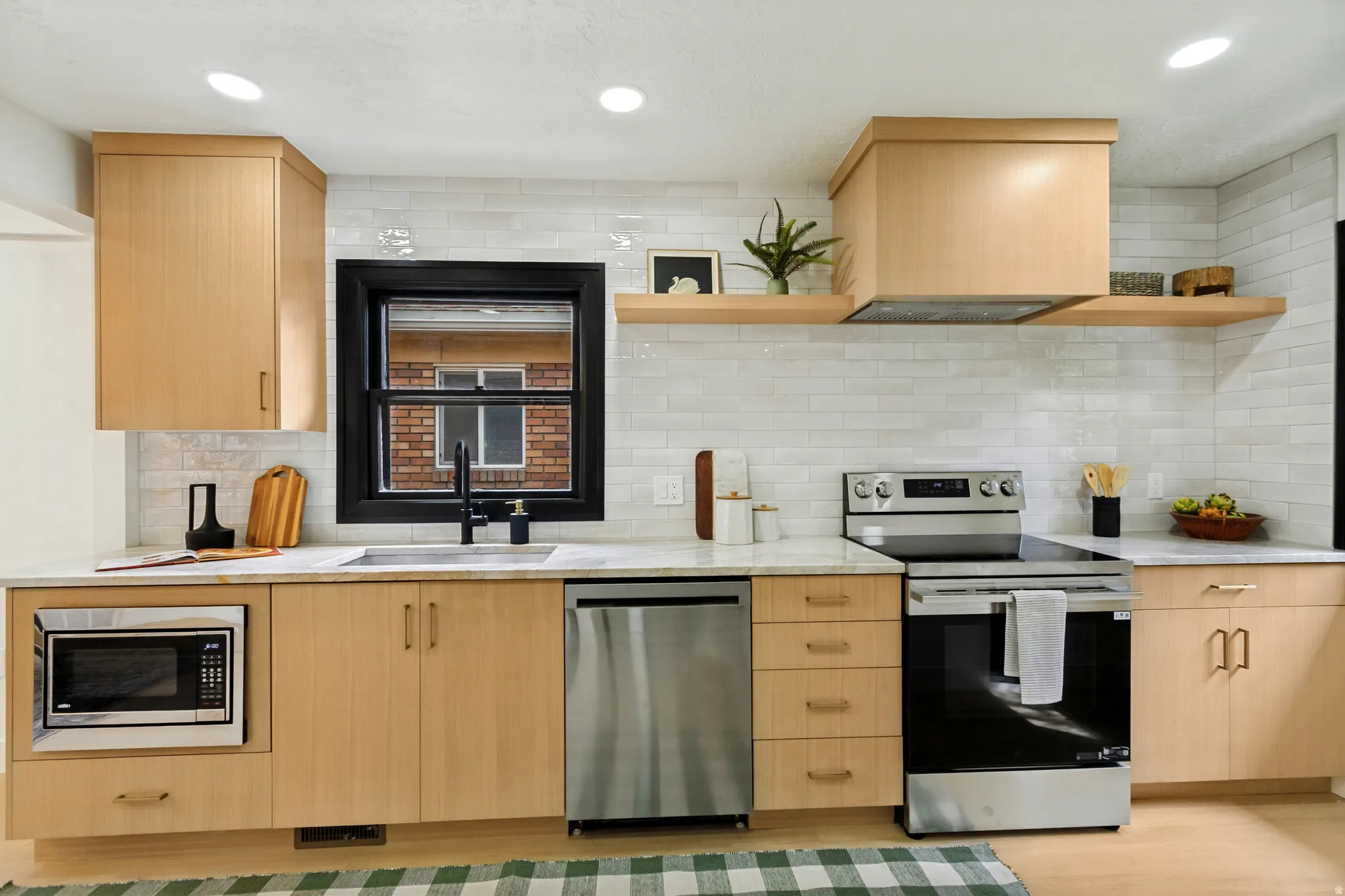 Light wood-finish cabinetry, stainless steel appliances, a white subway tile backsplash, light countertops, and recessed lighting