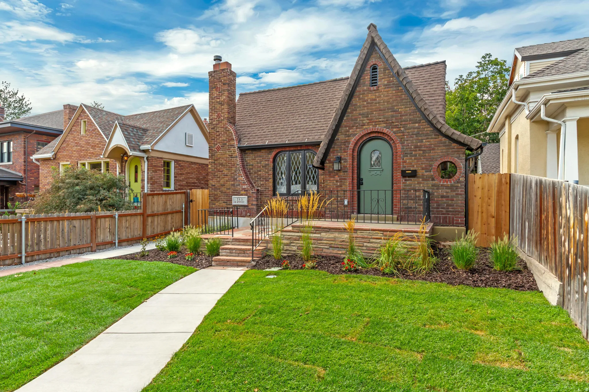 Brick facade with a prominent chimney, arched entryway, and dark-framed windows