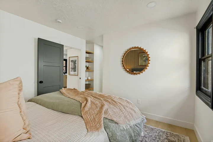 Recessed ceiling lighting, wood-finish flooring, dark-framed window, built-in shelving, and a panel-style door