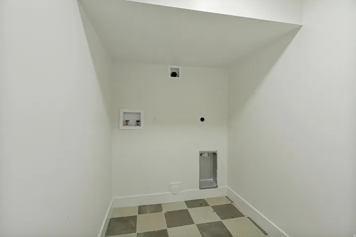 Utility room with checkerboard tile flooring and white walls