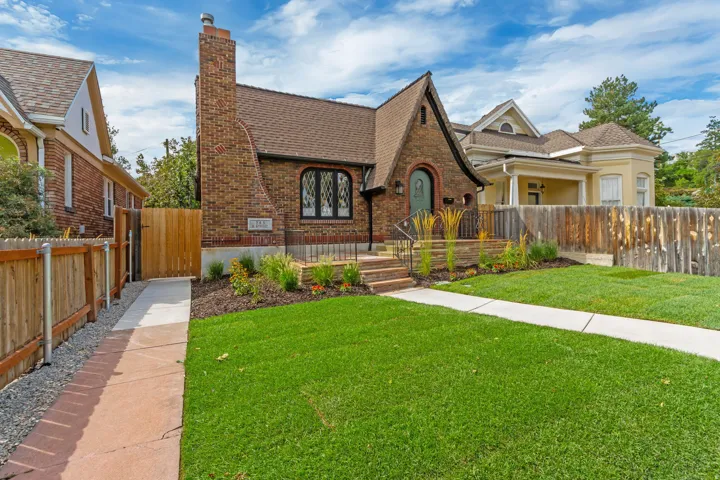Charming brick Tudor-style residence featuring a steeply pitched roof with decorative gabling, arched entryway with leaded glass detailing, and a brick chimney