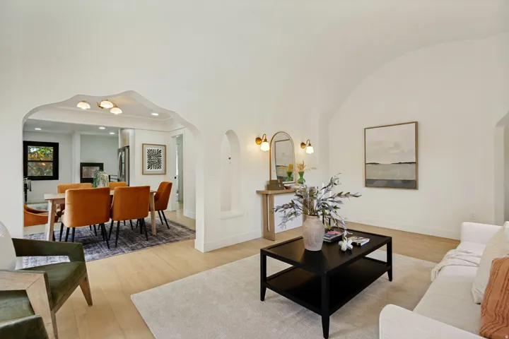 Vaulted ceiling, arched doorways, wood-finish flooring, recessed wall niche, and modern wall sconces