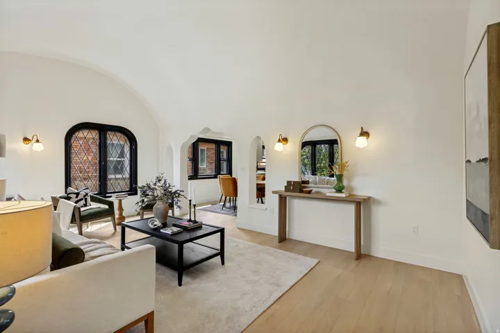 Arch-top windows with leaded glass, light wood-finish flooring, arched doorways, and wall sconces