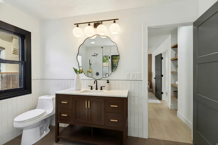 Dark wood-finish vanity with gold-tone hardware, white countertop, and matte black faucet