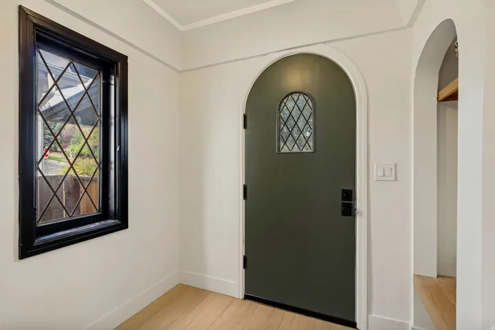 Arched entryway with a leaded glass door, complemented by a diamond-patterned window