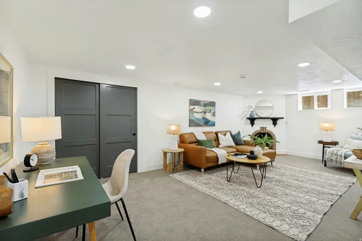 Recessed lighting, neutral carpeting, paneled sliding doors, and a brick fireplace with a mantel