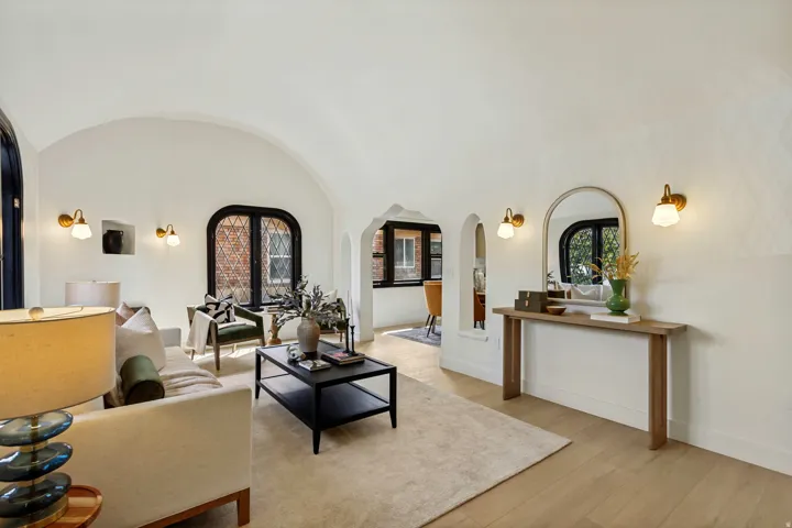 Vaulted ceilings, arched doorways, wood-finish flooring, recessed wall niche, and decorative wall sconces