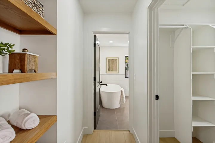 Integrated wood-finish shelving, substantial walk-in closet with built-in storage, and a freestanding soaking tub