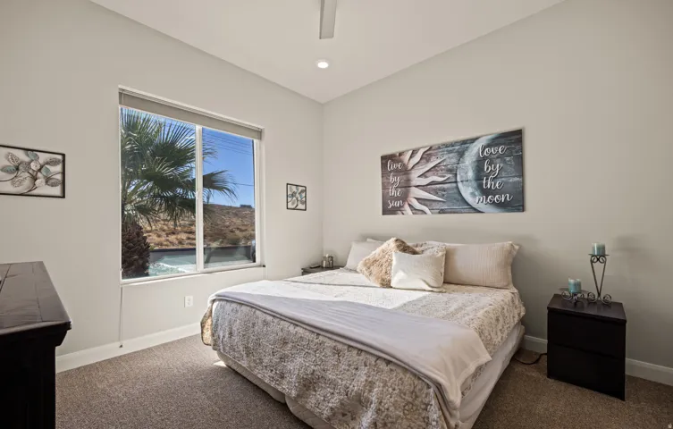Recessed lighting, ceiling fan, large window with roller shade, and neutral wall color