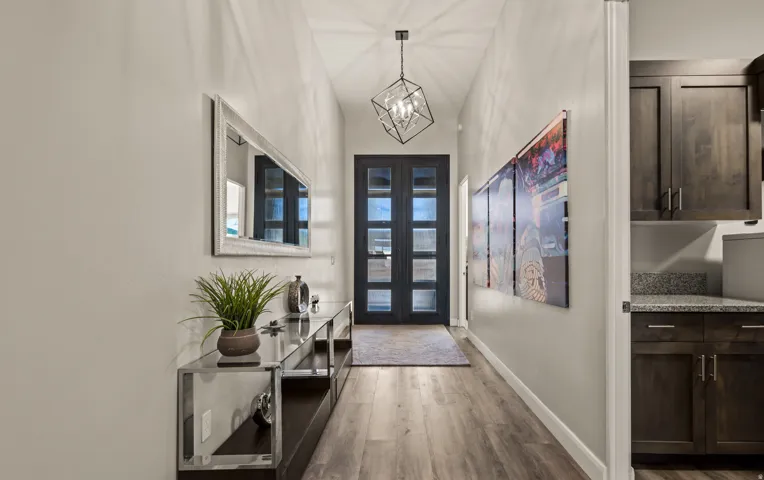 Entryway with wood-finish flooring, a geometric pendant light fixture, and a dark double entry door with glass panels