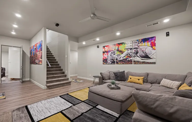 Recessed ceiling lighting, wood-finish flooring, carpeted staircase, ceiling fan, and built-in wall speakers