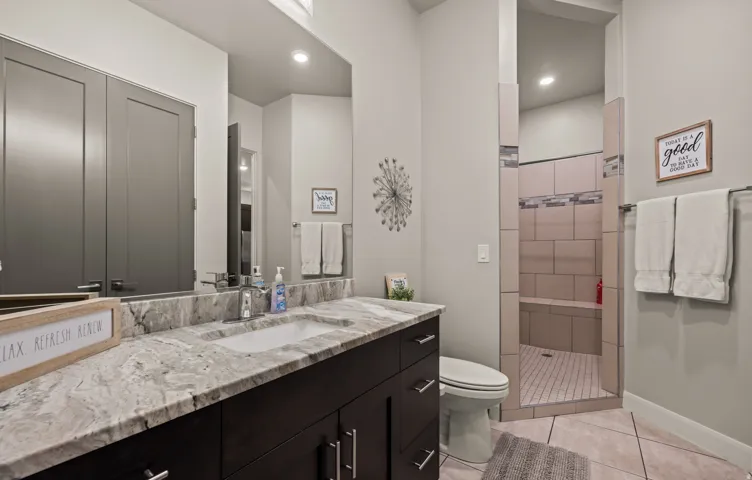Vanity with integrated sink, dark wood-finish cabinetry, and a patterned countertop