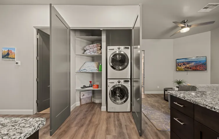 In-unit laundry closet with stacked appliances and built-in shelving