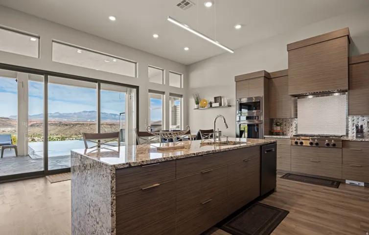 Kitchen featuring a large island with stone countertops, stainless steel appliances, wood-finish cabinetry, and wide sliding glass doors
