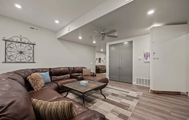 Recessed lighting, wood-finish flooring, ceiling fan, and gray bi-fold doors