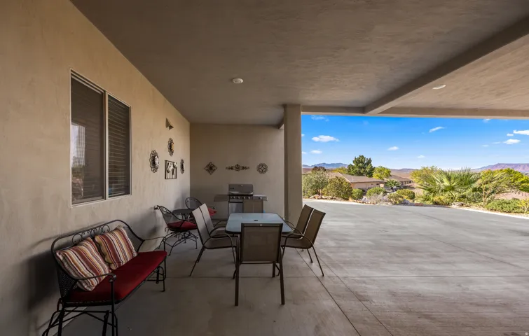 Expansive covered patio with polished concrete flooring and ceiling fans, framed by stucco walls and large sliding glass doors