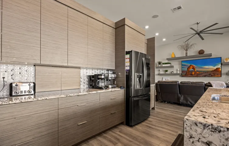 Modern kitchen cabinetry with integrated stainless steel appliances, granite countertops, and mosaic tile backsplash