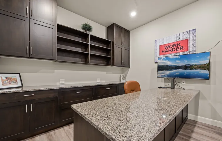 Built-in dark wood cabinetry, integrated shelving, stone countertops, and wood-finish flooring