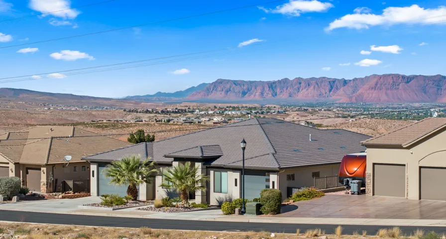 Modern desert residence featuring a clean-lined architectural design with a dark composite roof, integrated solar panel array, and multi-car garage with contemporary styling
